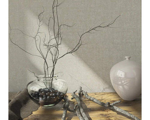 Arrangement décoratif avec vase en verre, branches et boules décoratives sur une table en bois.