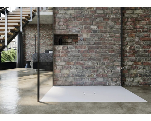 Douche à l''italienne avec receveur de douche plat devant un mur de briques dans une pièce aménagée de façon moderne.