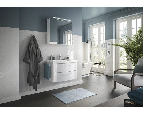 Salle de bain lumineuse avec meuble-lavabo, armoire de toilette, baignoire et fauteuil