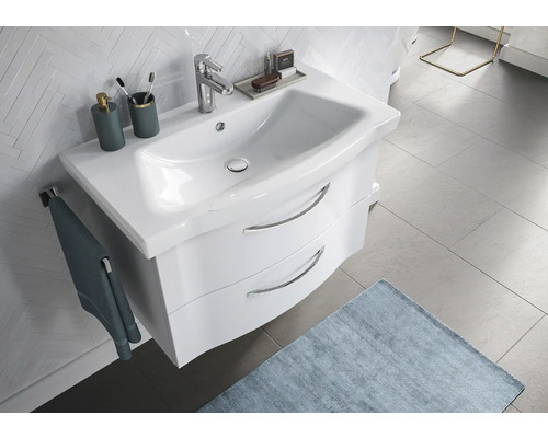 Meuble-lavabo avec meuble sous-lavabo, robinet, serviette et accessoires de salle de bain dans une salle de bain lumineuse.