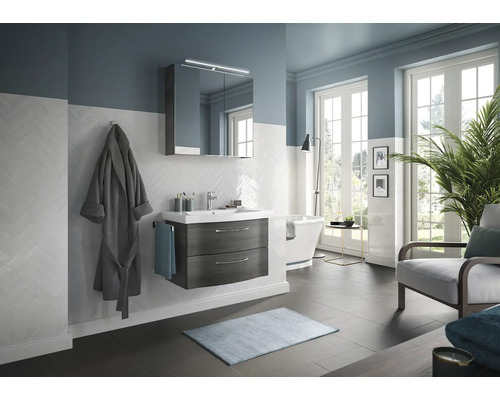 Salle de bain lumineuse avec meuble-lavabo, miroir, baignoire et fauteuil