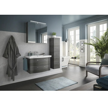 Helles Badezimmer mit Waschtisch, Spiegelschrank, Hochschrank, Badewanne und Sessel für ein modernes Ambiente.