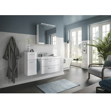 Salle de bain lumineuse avec meubles de salle de bain blancs, miroir, lavabo et baignoire.