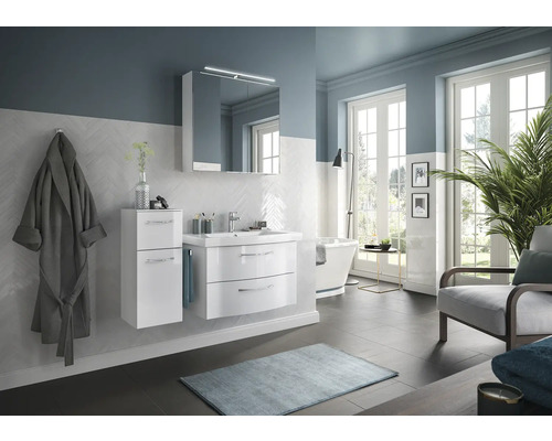 Salle de bain lumineuse avec meubles de salle de bain blancs, miroir, lavabo et baignoire.