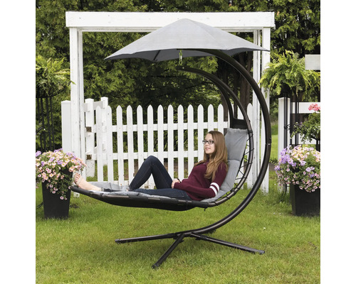 Frau entspannt in einem Hängeinsel-Sessel mit Sonnenschutz im Garten.