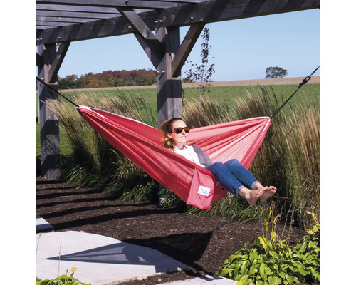 Eine Frau entspannt in einer roten Hängematte im Garten