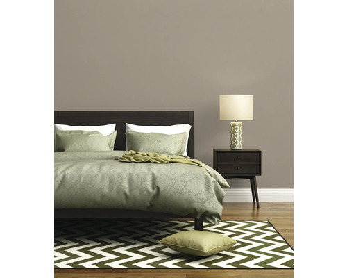 Schlafzimmer mit Bett, Nachttischlampe und gemustertem Teppich