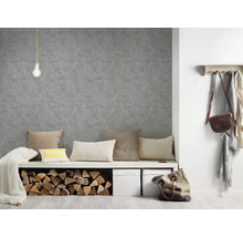 Wohnraumszene mit grauer Strukturtapete, Sitzbank mit Kissen und Holzscheiten