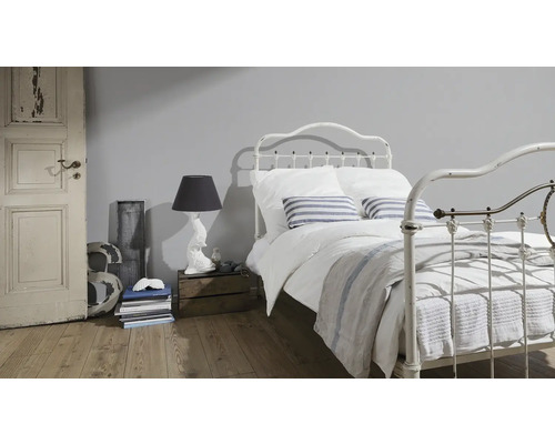 Chambre avec lit en métal, lampe de chevet et plancher en bois