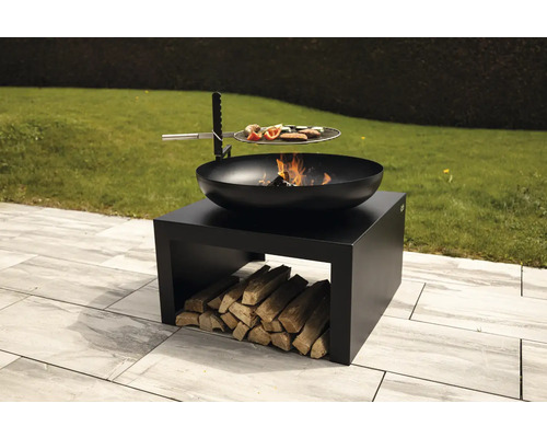 Brasero avec anneau de gril sur un stockage de bois dans un jardin