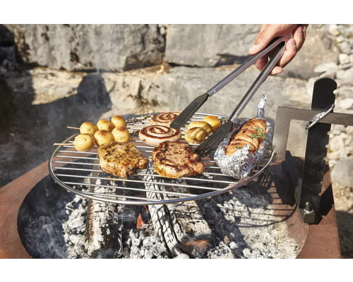 Gril avec steaks, saucisses, pommes de terre et pince à grillades sur feu ouvert