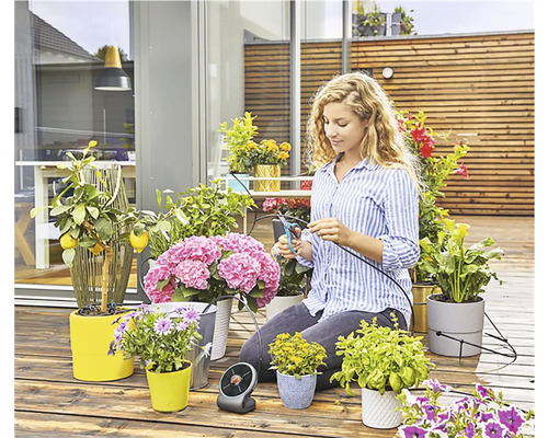 Femme coupant un tuyau d''arrosage pour plantes sur une terrasse