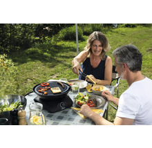 Scène d''extérieur avec un couple faisant un barbecue avec un grill de table, des grillades, des salades et des boissons