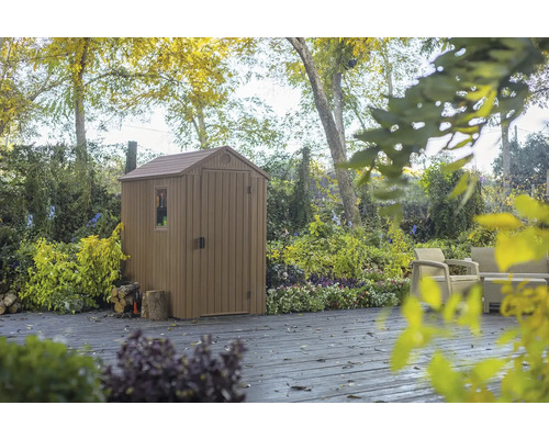 Gartenschuppen aus Kunststoff auf einer Terrasse mit Gartenmöbeln im Hintergrund