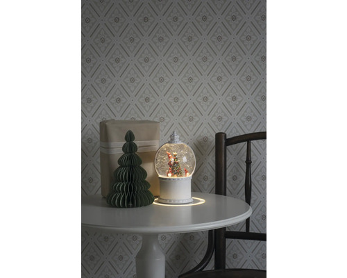 Arrangement décoratif avec boule à neige, cadeau et arbre en papier sur une table