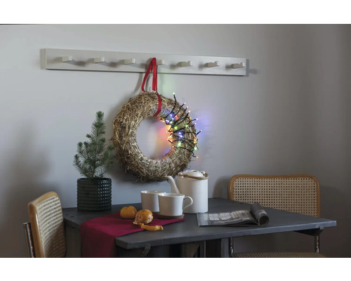 Nature morte décorative avec table, chaises, couronne, guirlande lumineuse et porte-manteau