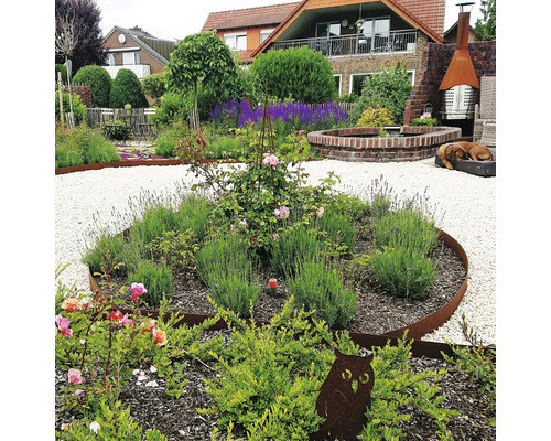 Jardin aménagé avec plantes, allées de gravier et décorations.