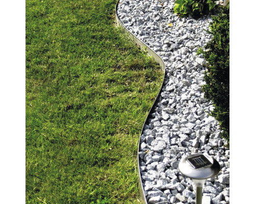 Scène de jardin avec pelouse, allée de gravier, bordure métallique et lampe solaire