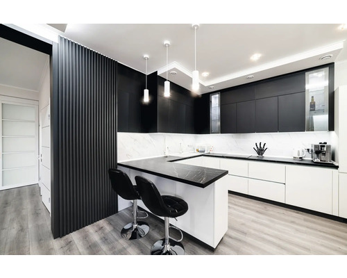 Cuisine moderne avec armoires noires et blanches, plan de travail en marbre et deux tabourets de bar.