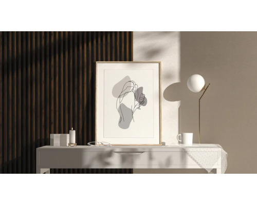 Dekoratives Bild mit abstrakter Frauendarstellung im Rahmen auf einem Tisch mit Lampe, Tasse und Kerze