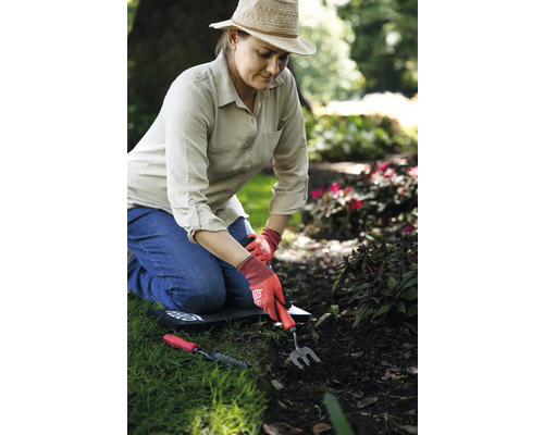 Femme travaille dans le jardin avec des outils à main et une protection des genoux