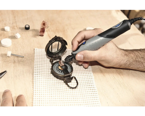 Hand, die mit einem Dremel-Werkzeug einen Kompass auf einer Holzoberfläche poliert