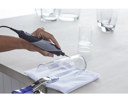 Dremel Logo. Hand schleift ein Glas mit einem Dremel Multifunktionswerkzeug. Glas ist mit einer Klemme befestigt.