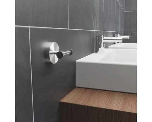 Salle de bain moderne avec murs carrelés gris, lavabos et crochet pour serviette.