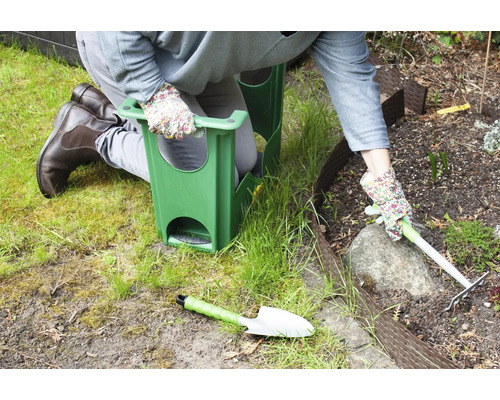 Personne agenouillée avec tabouret de jardin lors de travaux de jardinage avec râteau et pelle
