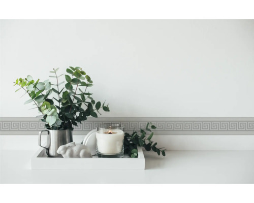 Bordure décorative à motif de méandre sur le mur au-dessus d''une table avec bougie et plante