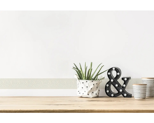 Bordure décorative sur un mur avec plante, lampe et récipients sur une table