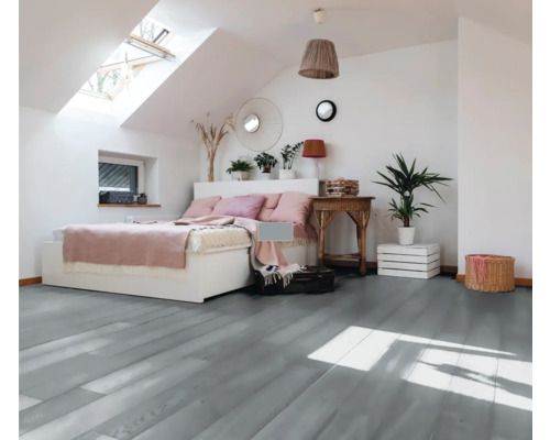 Schlafzimmer mit Dachfenster, Bett, Holzboden und dekorativen Elementen.