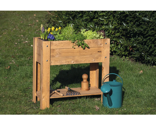 Jardinière en bois avec plantes, arrosoir et outils de jardin sur une pelouse