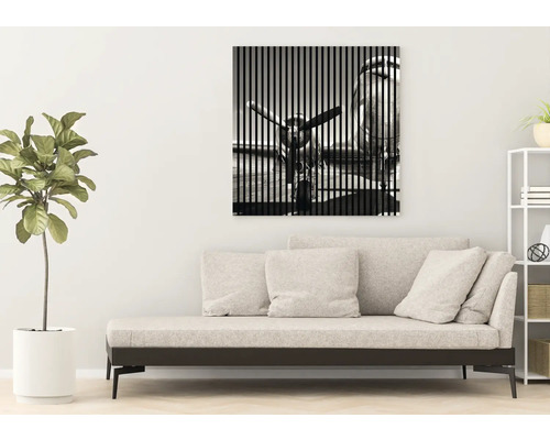 Wandbild mit Flugzeugmotiv über einer Couch im Wohnzimmer.