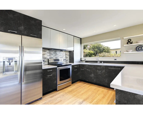 Cuisine moderne avec des appareils en acier inoxydable et des plans de travail sombres.