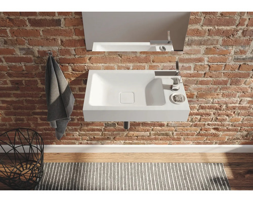 Salle de bain moderne avec lavabo, robinet et miroir sur un mur en briques