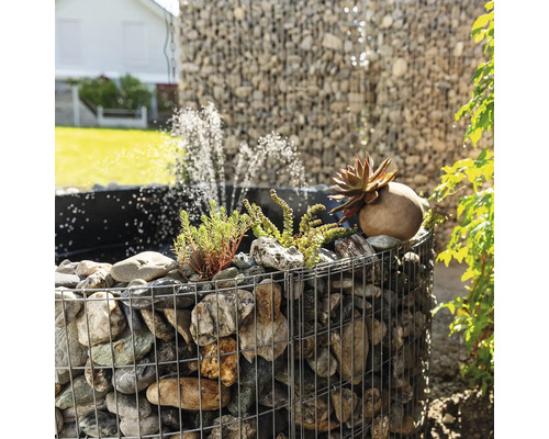 Fontaine en gabion avec pierres, plantes et jeux d''eau dans le jardin