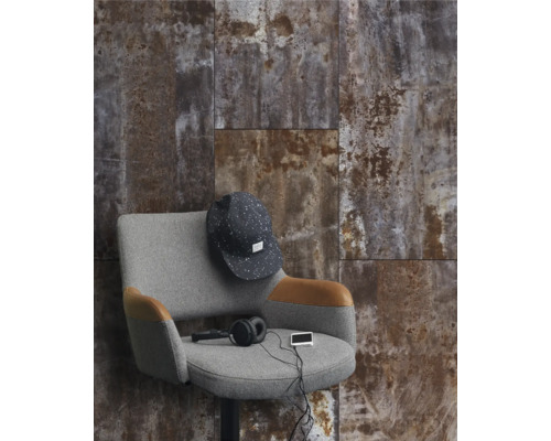 Aménagement mural avec des carreaux aspect rouille, combiné avec un fauteuil gris et des accessoires