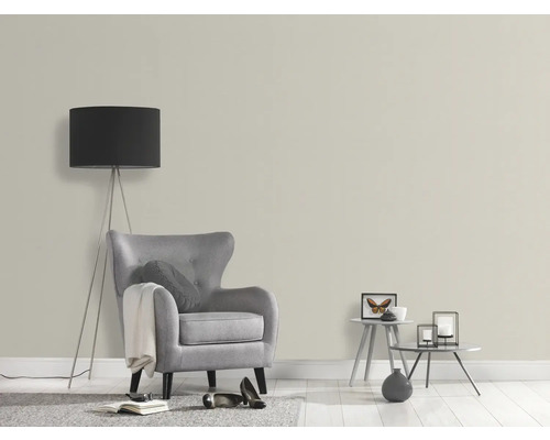 Wohnzimmer mit Sessel, Stehlampe und dekorativen Tischen vor einer hellen Wand