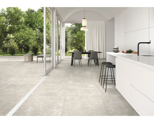 Heller Wohnraum mit Fliesenboden, Esstisch und offener Küche.