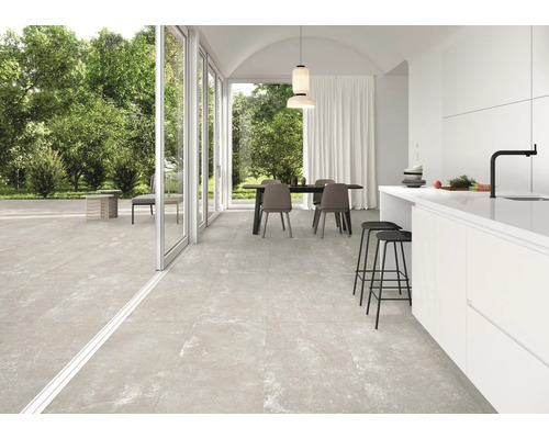 Pièce lumineuse avec table à manger, cuisine et carrelage de sol grand format