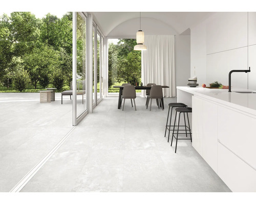 Espace de vie carrelé et lumineux avec coin repas et accès à la terrasse.