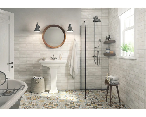 Helles Badezimmer mit Dusche, Waschbecken, Spiegel und gemusterten Bodenfliesen.