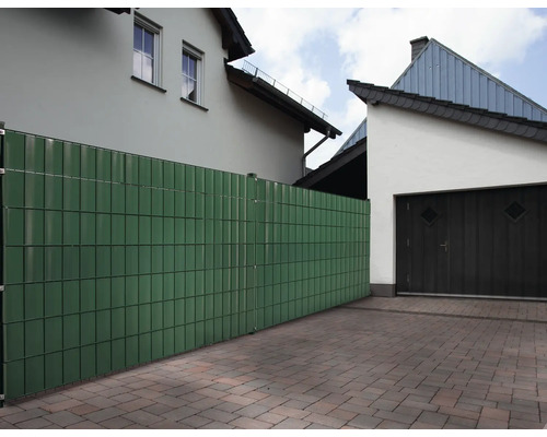 Clôture de jardin composée d''éléments en plastique devant des maisons