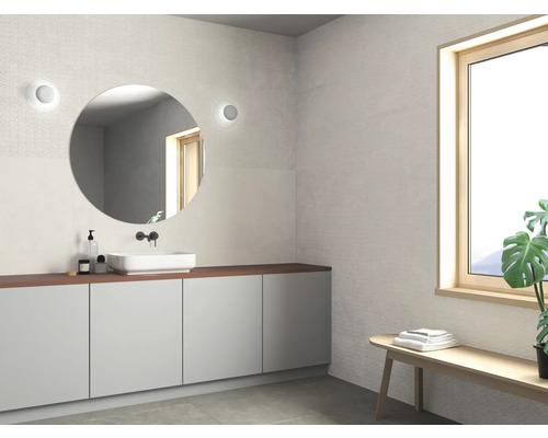 Salle de bains lumineuse avec lavabo, miroir et banc sous une fenêtre.