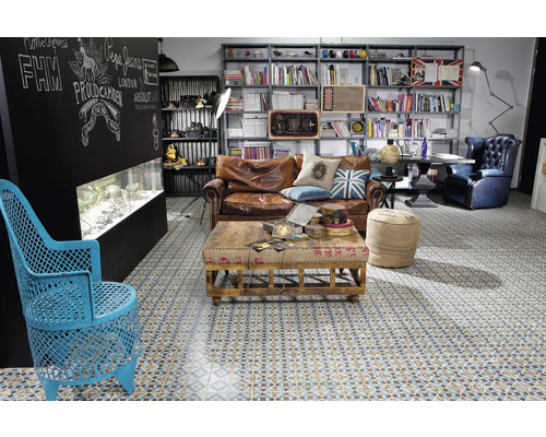 Salon avec canapé en cuir marron, table basse, bibliothèque et carrelage à motifs.