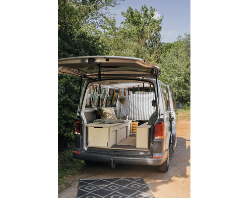 Fourgon aménagé avec aménagements intérieurs en bois et tapis devant le véhicule.