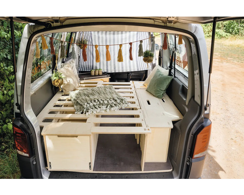 Fourgon aménagé avec lit, tiroirs, coussins et éléments décoratifs