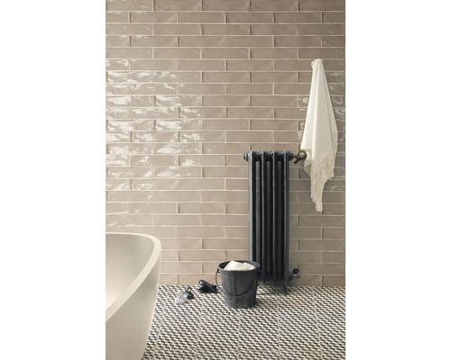 Salle de bain avec carrelage mural, radiateur et baignoire.