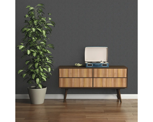 Exemple d''aménagement intérieur avec commode, tourne-disque et plante d''intérieur devant un papier peint à motifs.